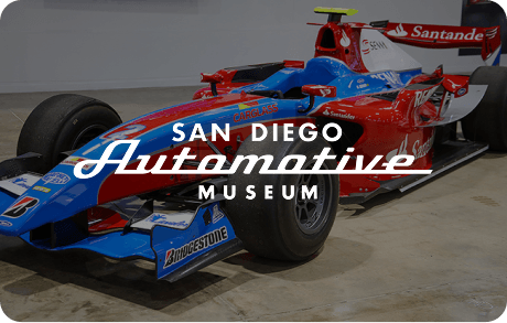 San Diego Automotive Museum's logo over an image of Formula One car on display at the museum